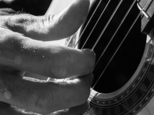Foto en blanco y negro. Primer plano de la mano de Martí Batalla tocando la guitarra.