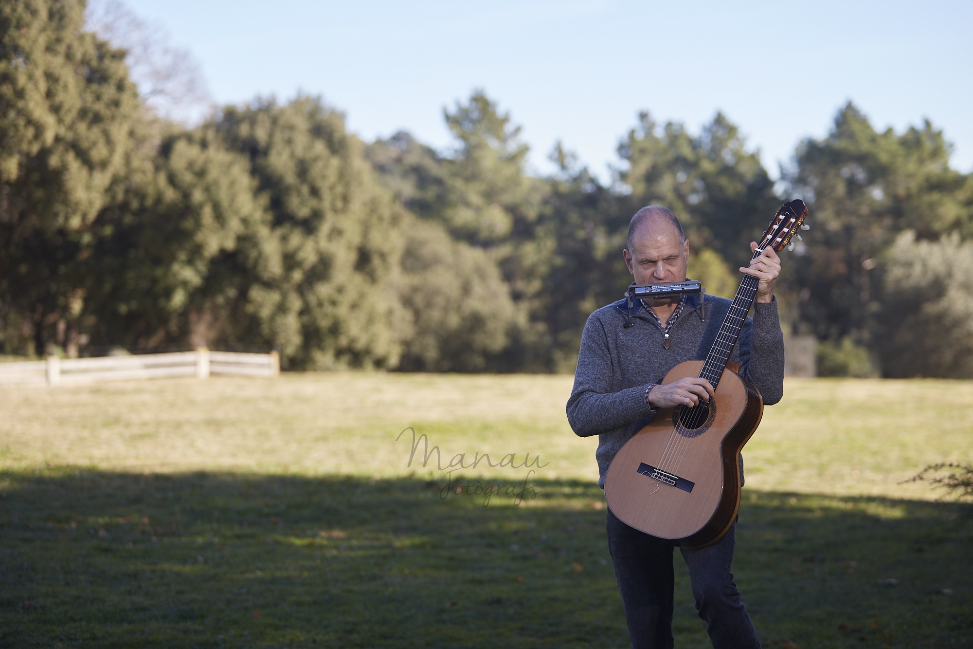 Imagen de Martí Batalla de pie en un prado con su guitarra y su harmónica